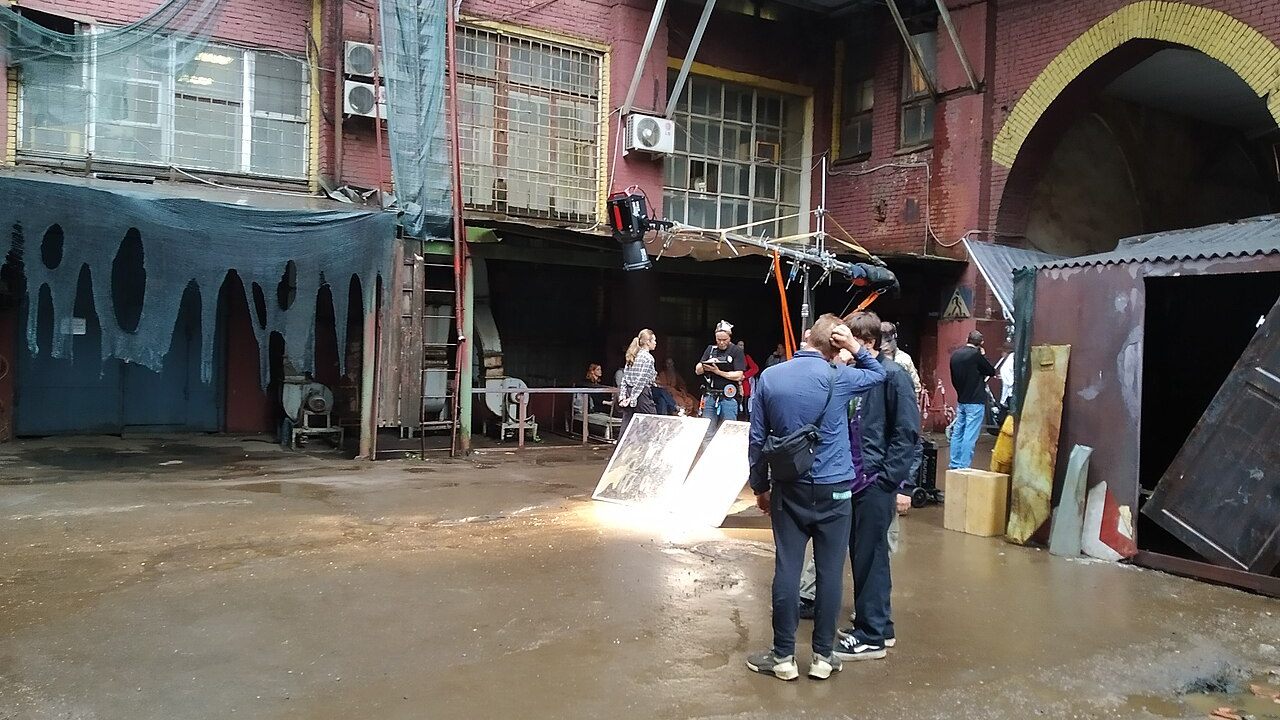Film set with a camera rig and lighting equipment under a canopy